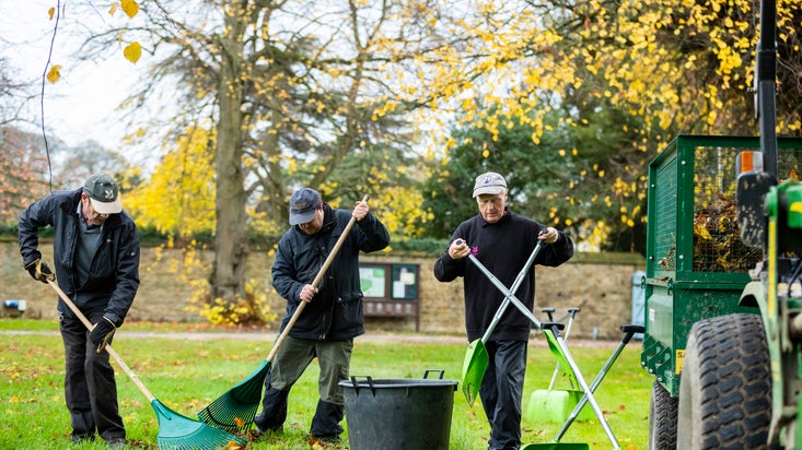 Gardeners clearing away autumn leaves